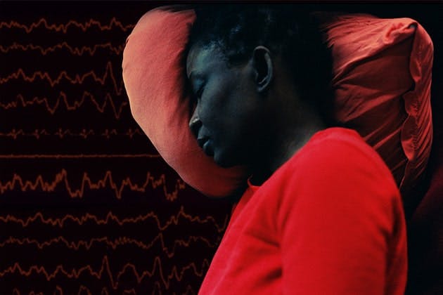 Cutout photo of person sleeping with a pillow superimposed on a background of repeating EEG readings.