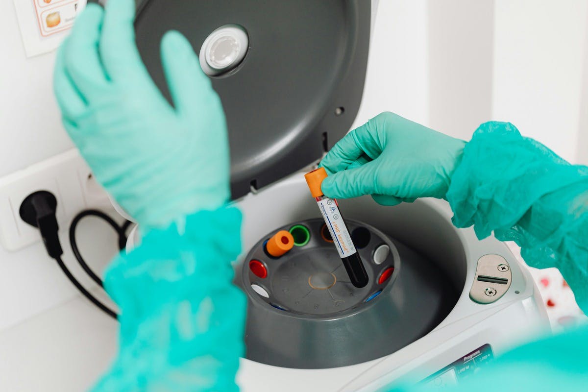 Photo of medical professional putting vials of blood into a centrifuge, a device that can spin blood at such a speed as to separate it into its various components.