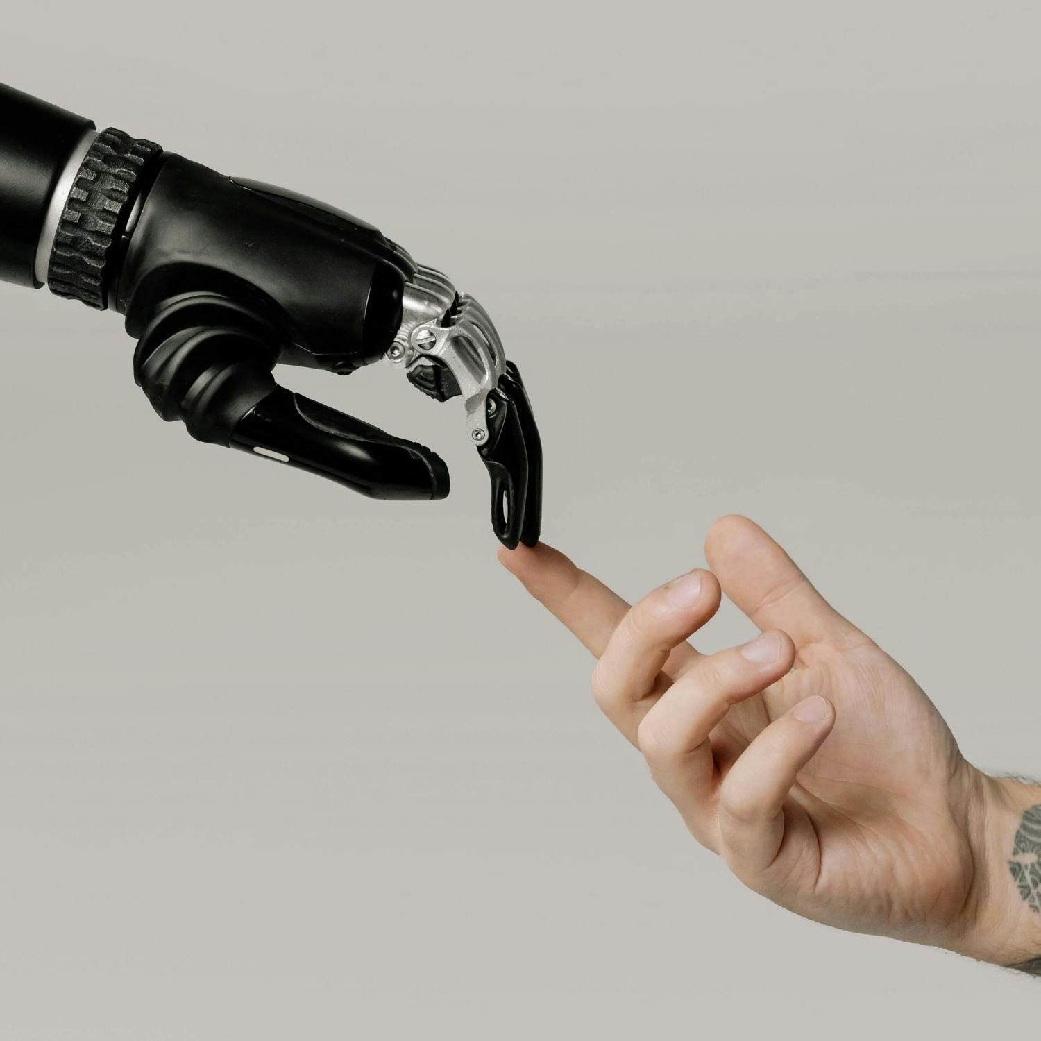 Photo of bionic arm reaching out to touch the fingertips of a human hand.