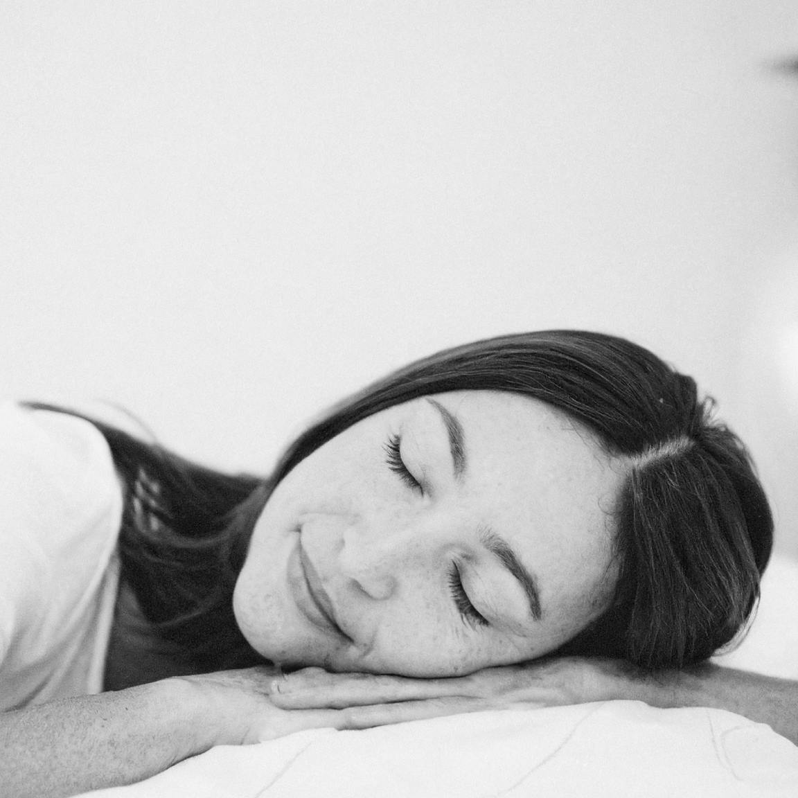 Person smiling as they lay their head on a pillow.