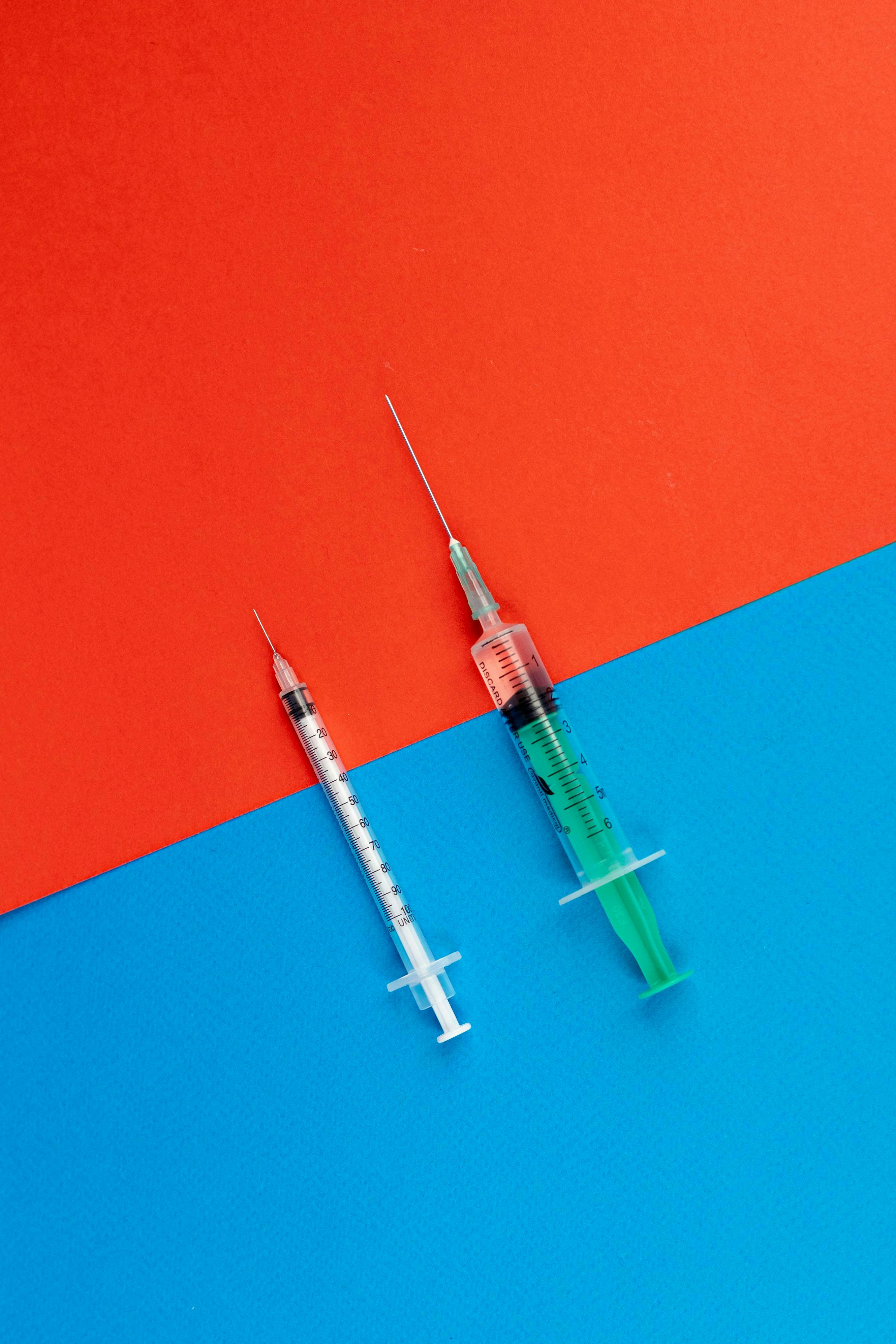 Staged photo of two syringes on flat surface.